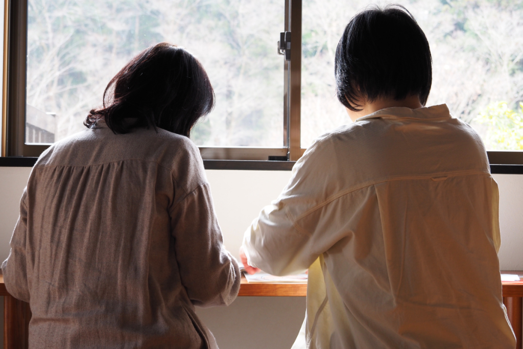 窓辺で向かい合って学ぶ2人の女性セラピスト。静かな環境で感性を育む様子
