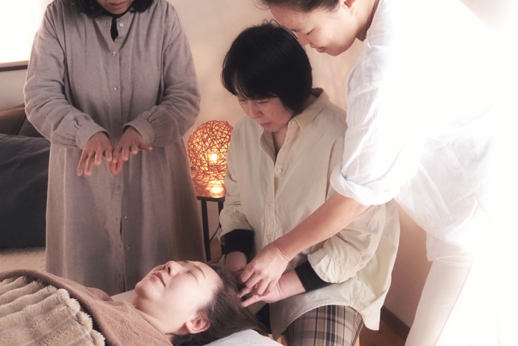 講師が受講生に対してお顔ほぐしの手技を丁寧に指導している様子。少人数で集中して学ぶセラピストのリトリート風景